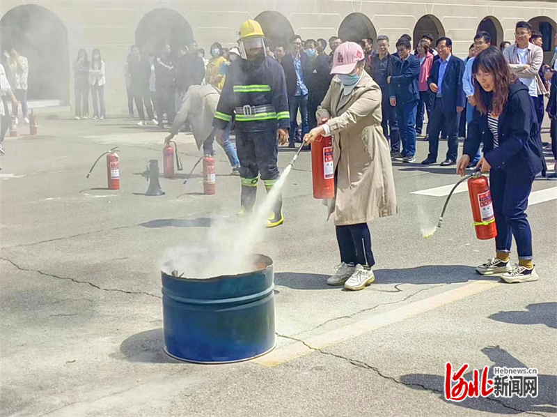 图为唐山海运职业学院教职工正在练习使用灭火器。