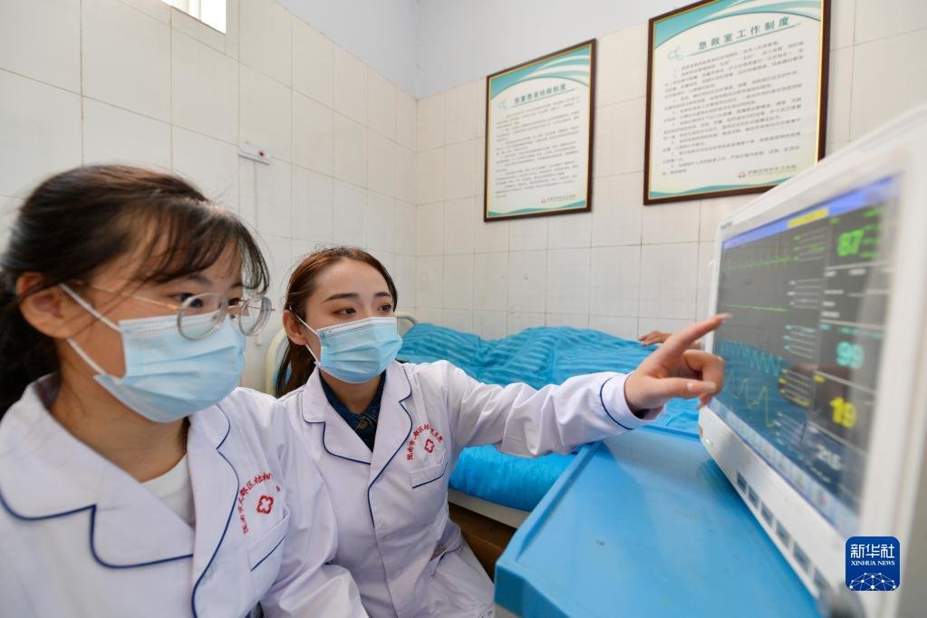 在武都区桔柑镇卫生院，李瑞（右）给同事讲解心电监护仪各项数值正常范围（5月11日摄）。新华社记者 范培珅 摄