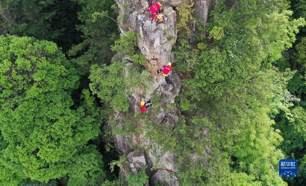 5月14日，张家界市武陵源区山地应急救援队队员系上绳索在悬崖峭壁间捡拾垃圾（无人机照片）。