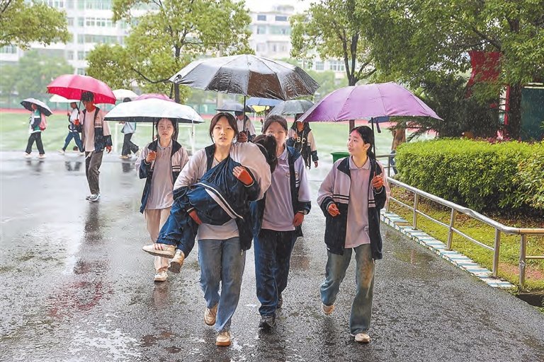 5月10日，新余市分宜三中初二学生张可心等人在雨中抱着不能行走的小雨到教室上课，成为校园里一道感人的风景线。