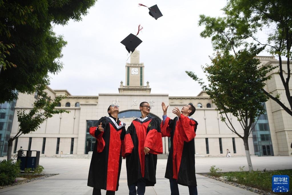 谢炎廷（中）和同学在兰州大学图书馆前拍“毕业照”留念（5月10摄） 新华社记者 陈斌 摄