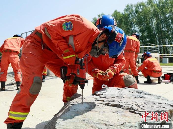 消防救援人员正在打岩钉固定锚点。　宋振豪 摄