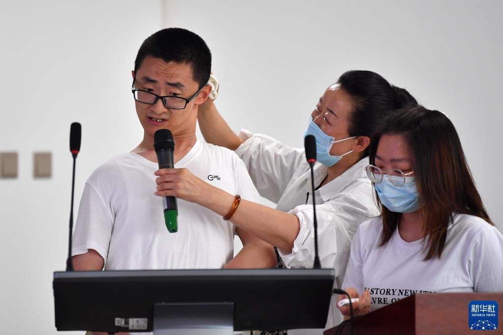 5月24日，谢炎廷（左）在兰州大学数学与统计学院进行论文答辩，母亲刘小凤（中）在一旁为他擦汗。新华社记者 陈斌 摄