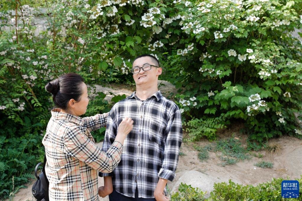 在兰州大学，母亲刘小凤帮谢炎廷整理衣服（5月12日摄）。新华社记者 方欣 摄