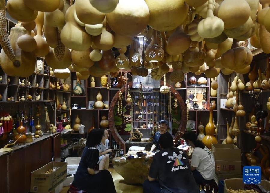 5月24日，来访者在曹魏古城一家非遗项目店铺内听葫芦烙画技艺介绍。新华社记者 鲁鹏 摄