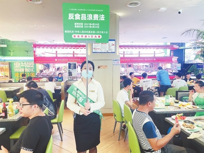 工作人员在餐厅举牌提醒顾客不要浪费。 江西日报全媒体记者 蔡颖辉摄