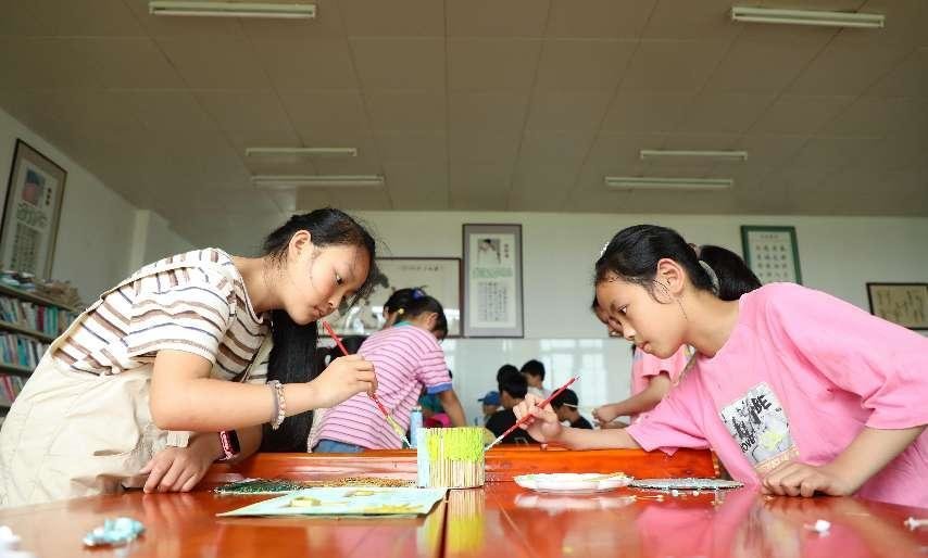 （6月2日，在肥西县铭传乡中心学校，学生给秸秆制作的环保手工艺品上色。 刘少芬 摄）