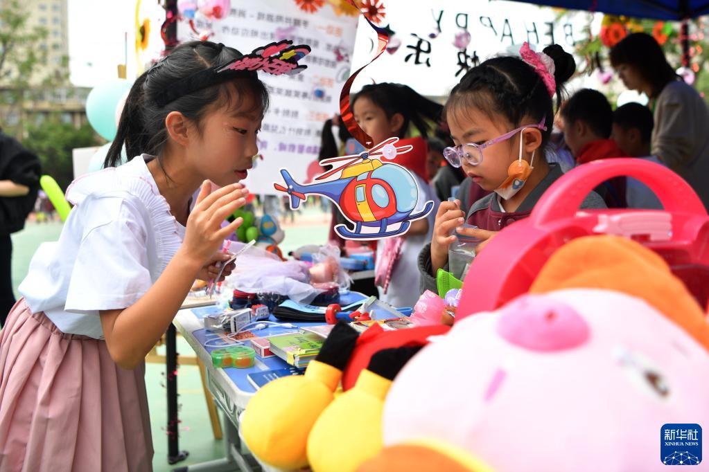 5月31日，兰州市东郊学校的小学生在创意义卖市集上挑选物品。新华社记者 陈斌 摄