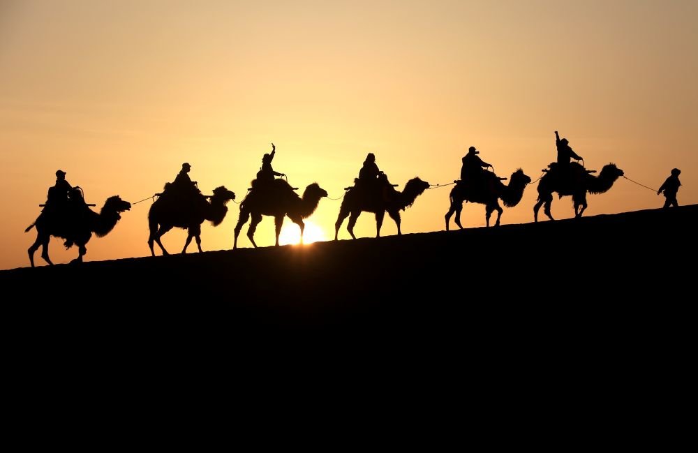 5月19日，游客在甘肃省敦煌鸣沙山月牙泉景区骑骆驼游览。新华社发（张晓亮 摄）