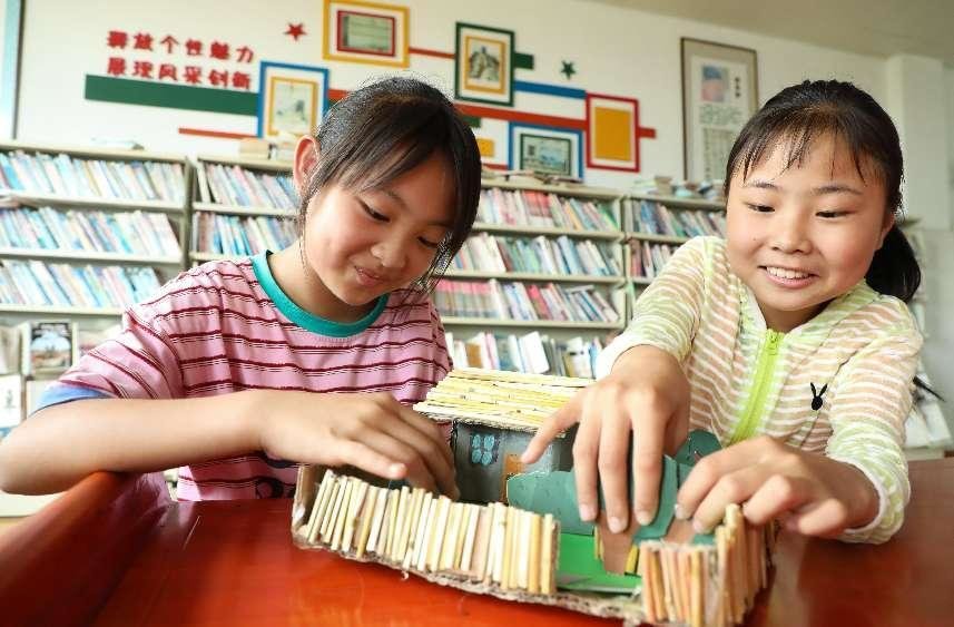 （6月2日，在肥西县铭传乡中心学校，学生用秸秆制作环保手工艺品。 陈家乐 摄）
