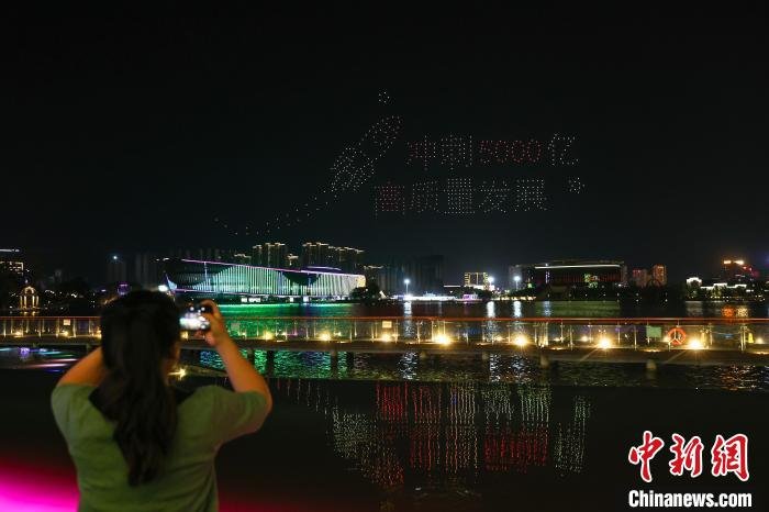 图为市民在用手机拍摄绚丽的无人机灯光秀表演。　刘力鑫 摄