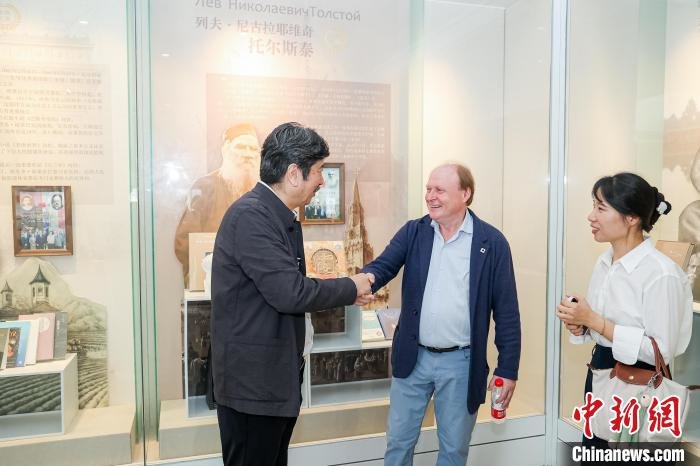 周令飞(左)和弗拉基米尔&middot;托尔斯泰(中)交谈并握手 主办方 供图