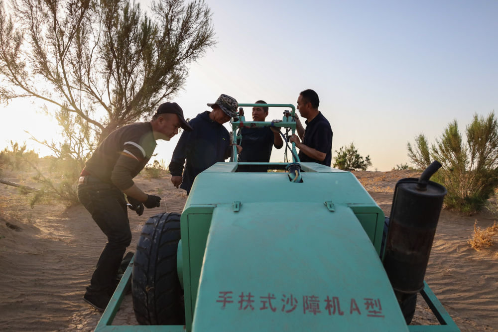 5月31日，武威市民勤县薛百镇的农民们使用新一代手扶式沙障机压草方格。