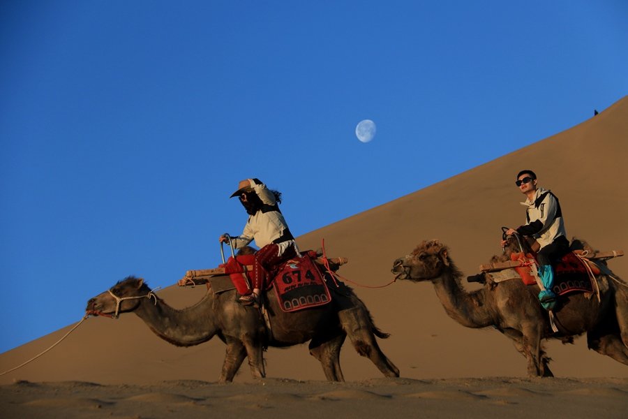 6月7日清晨，游客在甘肃省敦煌市鸣沙山月牙泉景区游览。张晓亮摄