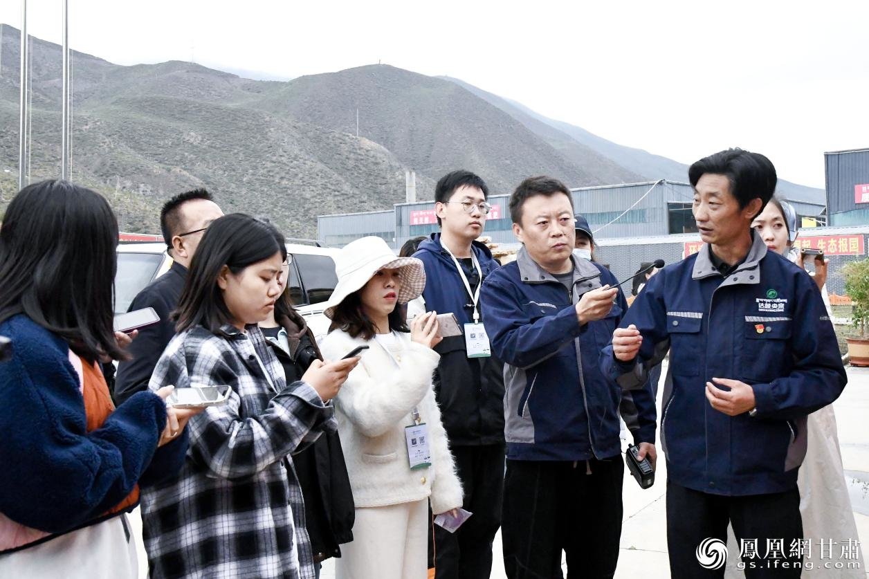 甘肃达哇央宗现代农业集团党支部书记范玉春（右一）在向采访团介绍有机肥的优点 李杨 摄