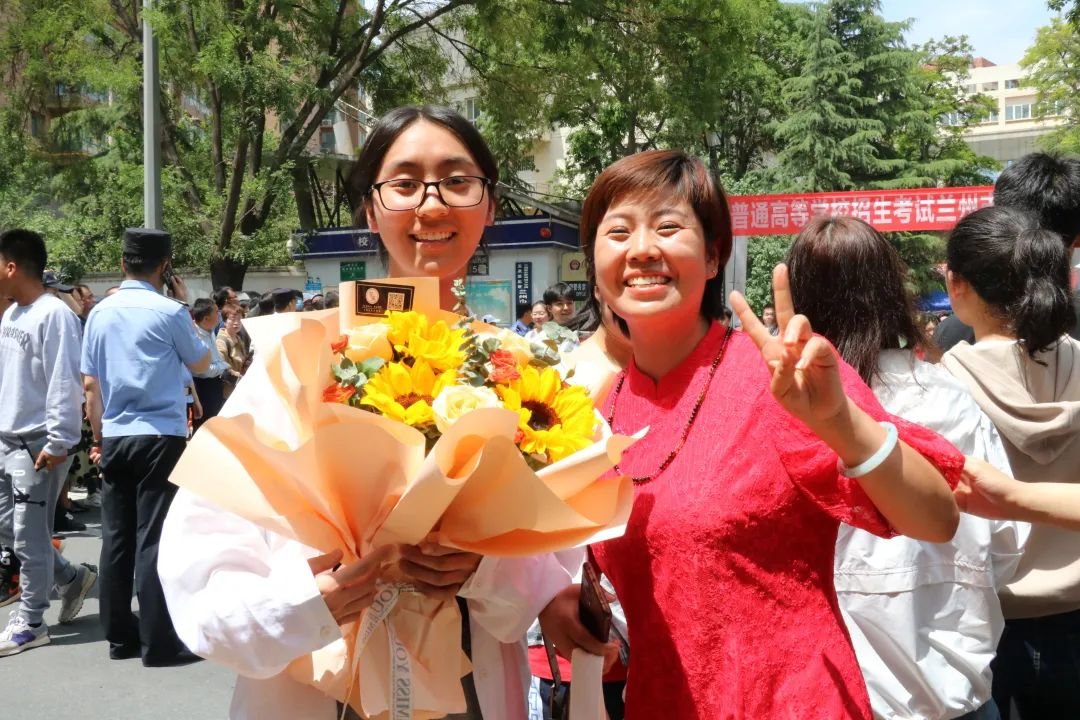 考试结束，在兰州市第二十七中学考点，妈妈为走出考场的女儿送上鲜花和祝福 。