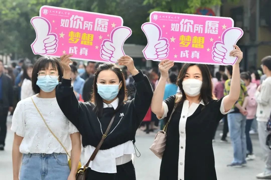 兰州四中考点外，第九中学老师为考生举牌加油。