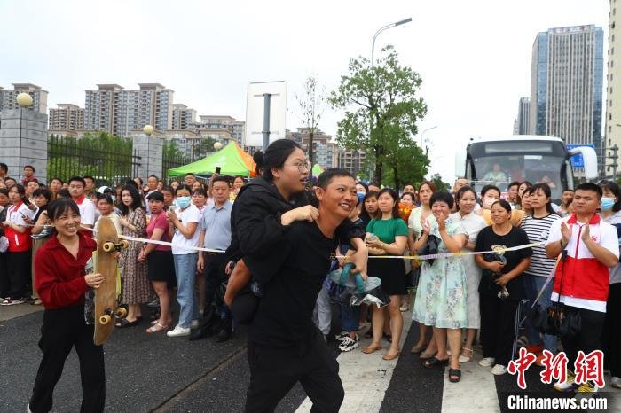 图为蒋张子怡的父亲背着她往外走，母亲拿着女儿的滑板跟在后面。　刘占昆 摄