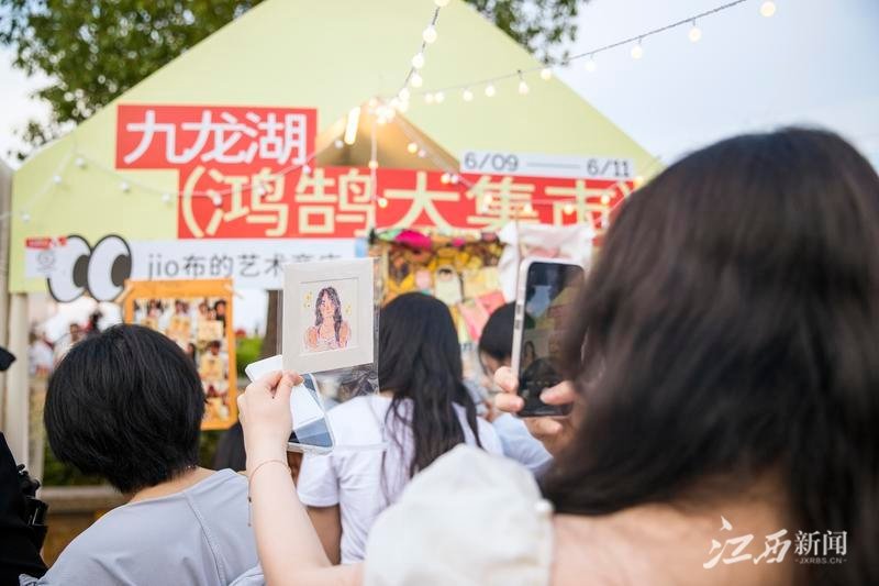 6月10日下午，游客在九龙湖&middot;鸿鹄大集市一网红摊位前拿着刚画好的自画像拍照。