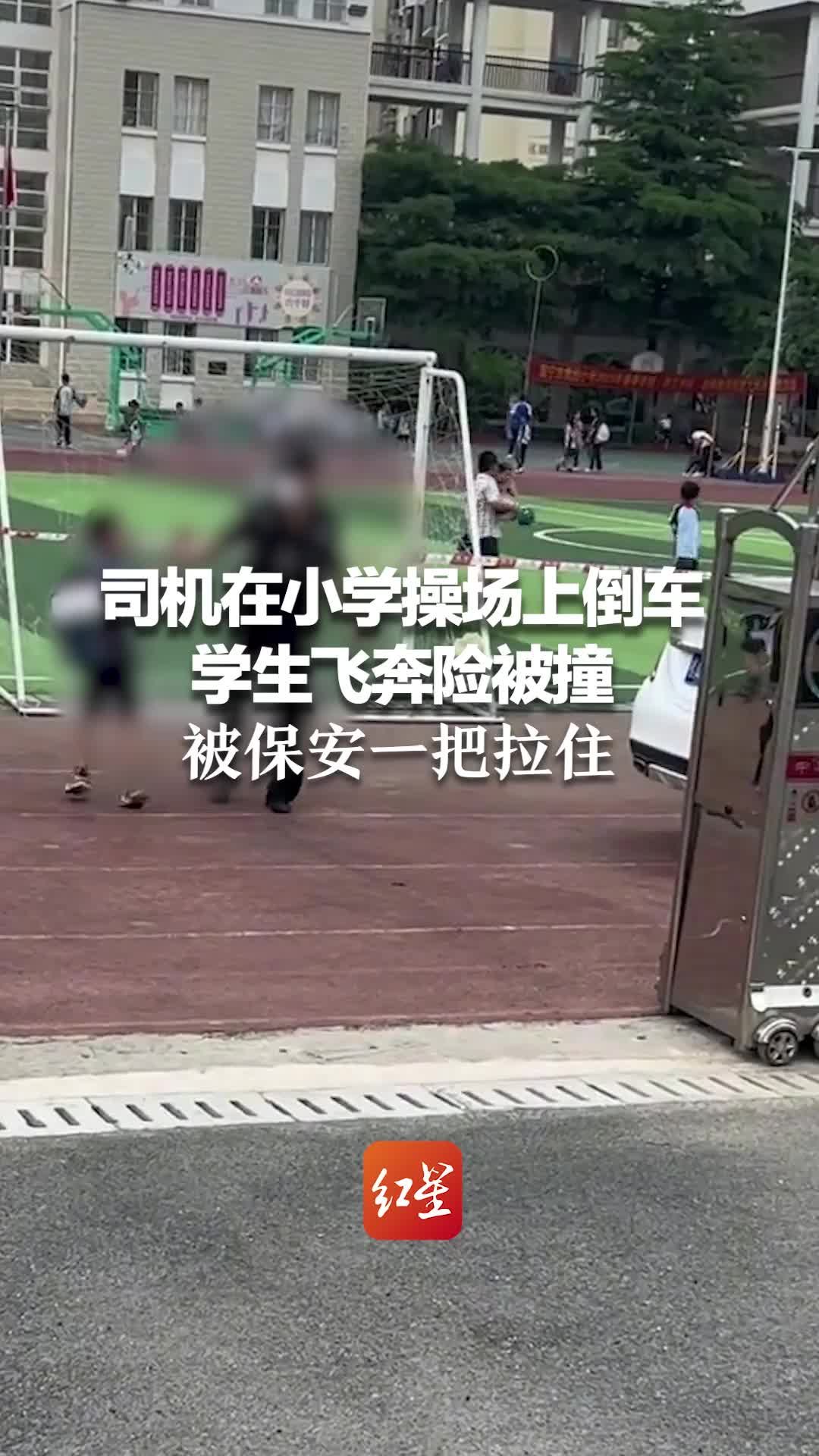 白色轿车司机在小学操场上倒车 学生飞奔险被撞 被保安一把拉住