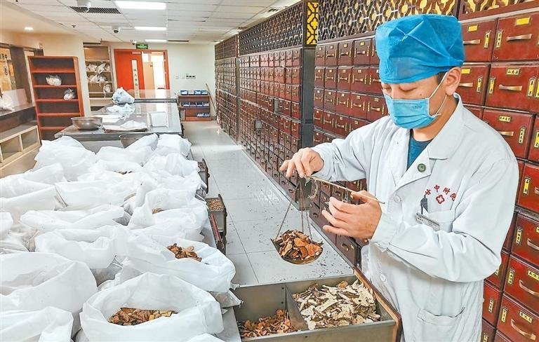 甘肃中医药大学附属医院中药房内药师为患者抓取中药 甘肃中医药大学附属医院供图