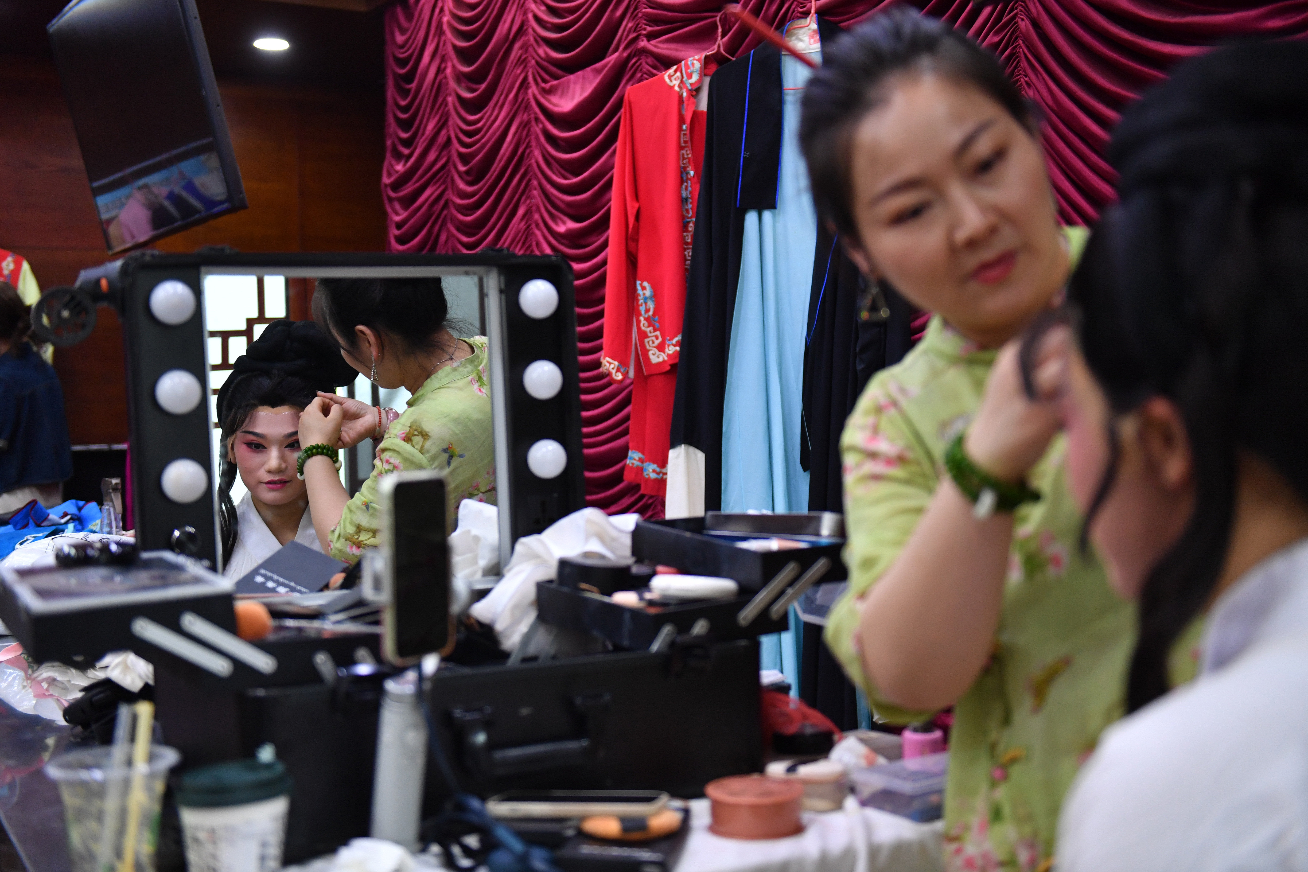 6月5日，在长沙市坡子街火宫殿，长沙市花鼓戏保护传承中心的演员在演出前整理头饰。新华社记者 陈振海 摄