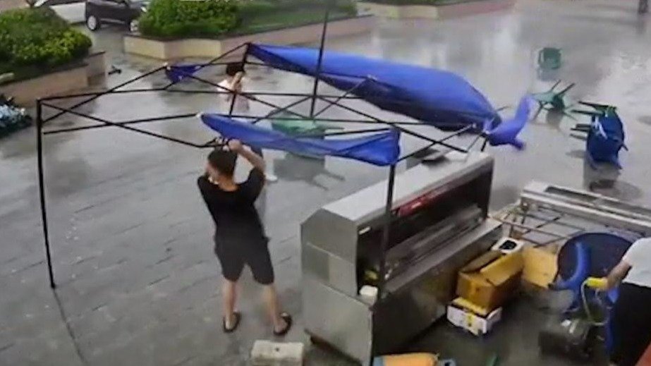 大风天烧烤店员试图拉住雨棚，连人带物被吹到一边