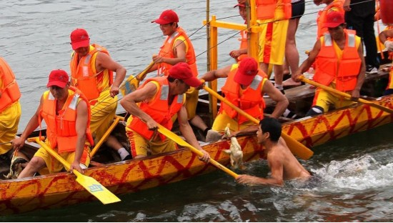 安康小伙从水中抓到鸭子后回到龙舟上