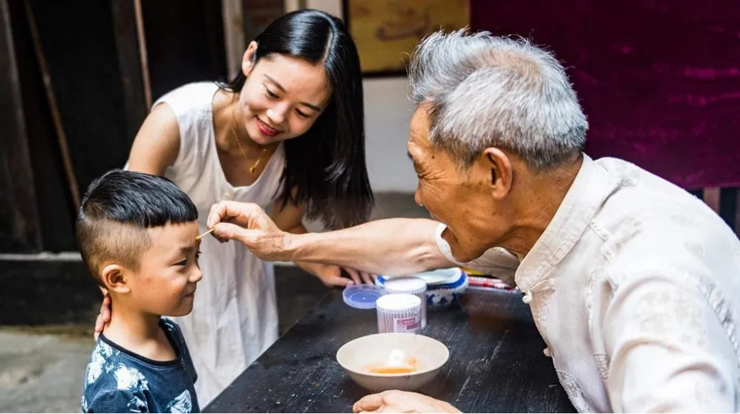 老人正在给小孩的额头上点雄黄酒