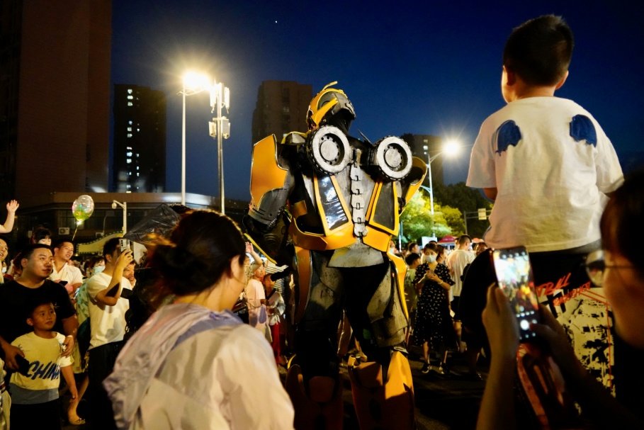 坐在爸爸肩上的小男孩紧盯机器人，寸步不离。