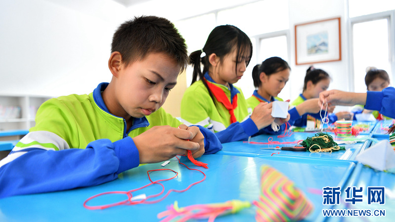 图为湖北省襄阳市保康县马桥镇尧治河村小学学生在制作"彩粽"香包.