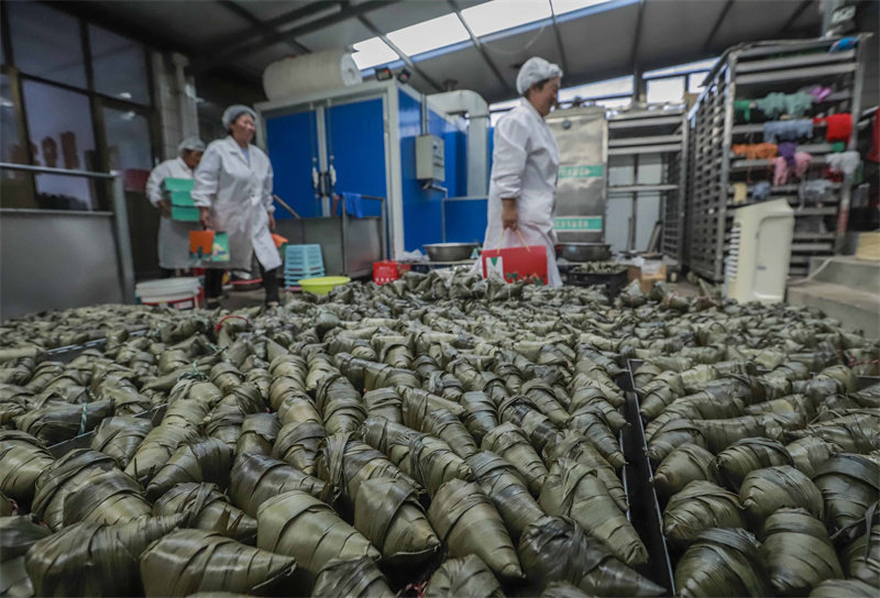 6月16日，工人在河北省迁西县东莲花院镇一家食品加工企业粽子生产车间搬运粽子准备蒸煮。