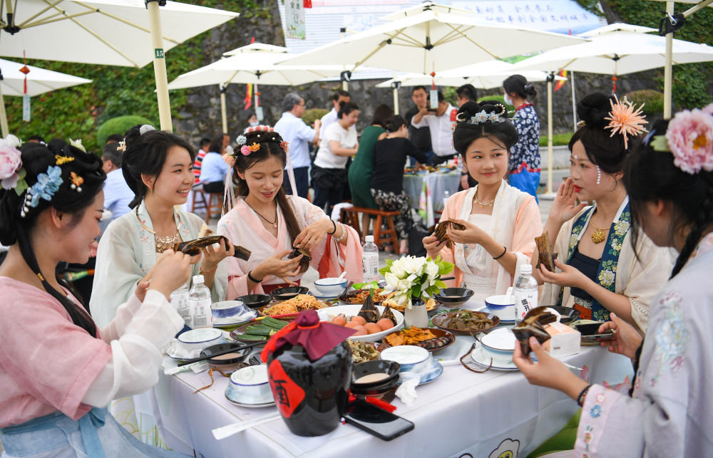 游客在第23届中国安康龙舟节的“汉江排子席”上品尝美食（6月22日摄）。新华社发（邹竞一摄）
