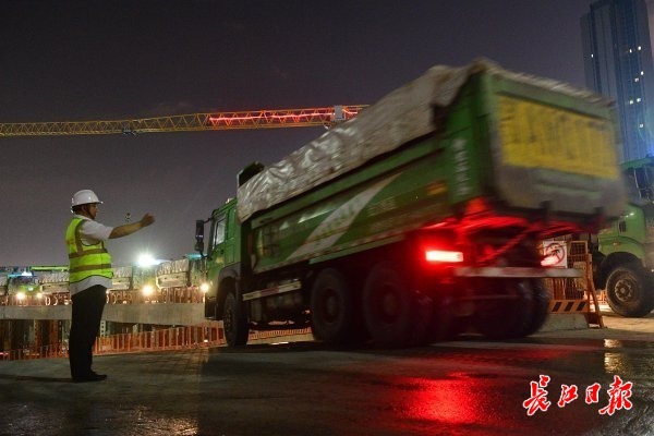 施工人员在基坑进出口指挥渣土车有序进出。 记者李永刚 摄