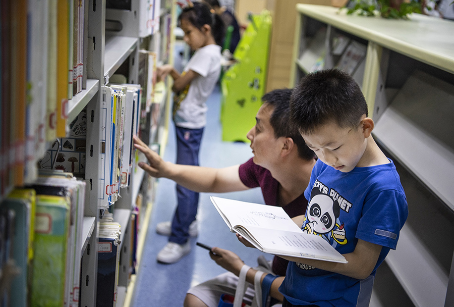 7月2日,一位小朋友在陕西省图书馆儿少阅室书柜查阅图书.