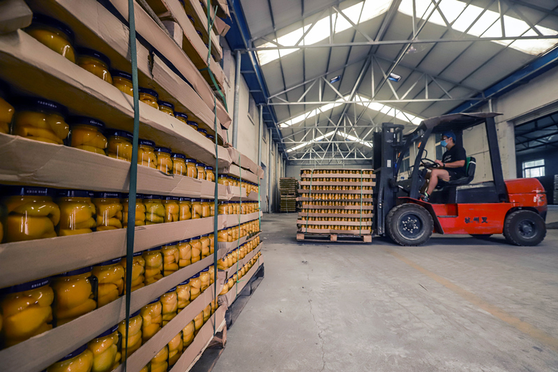 7月4日，工人在遵化市一家罐头生产企业仓库码放搬运桃罐头，准备外运。新华社发（刘满仓 摄）