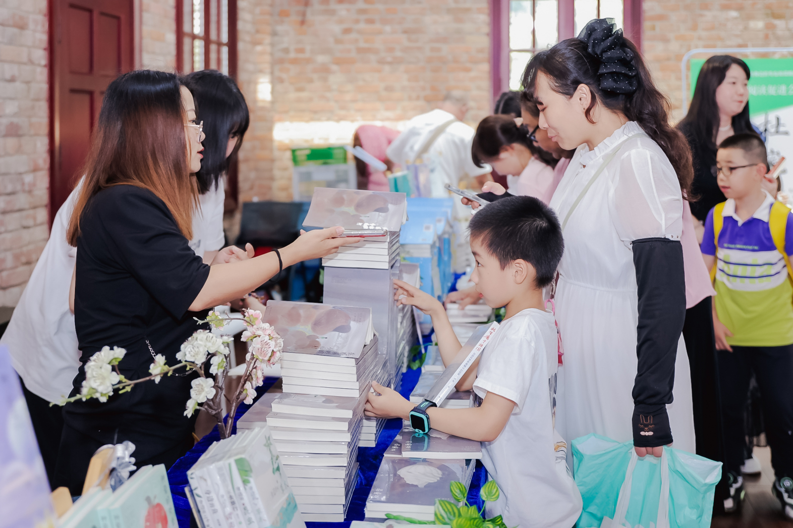 第十一届社区亲子读书节活动现场，亲子家庭在图书展台前挑选喜爱的图书