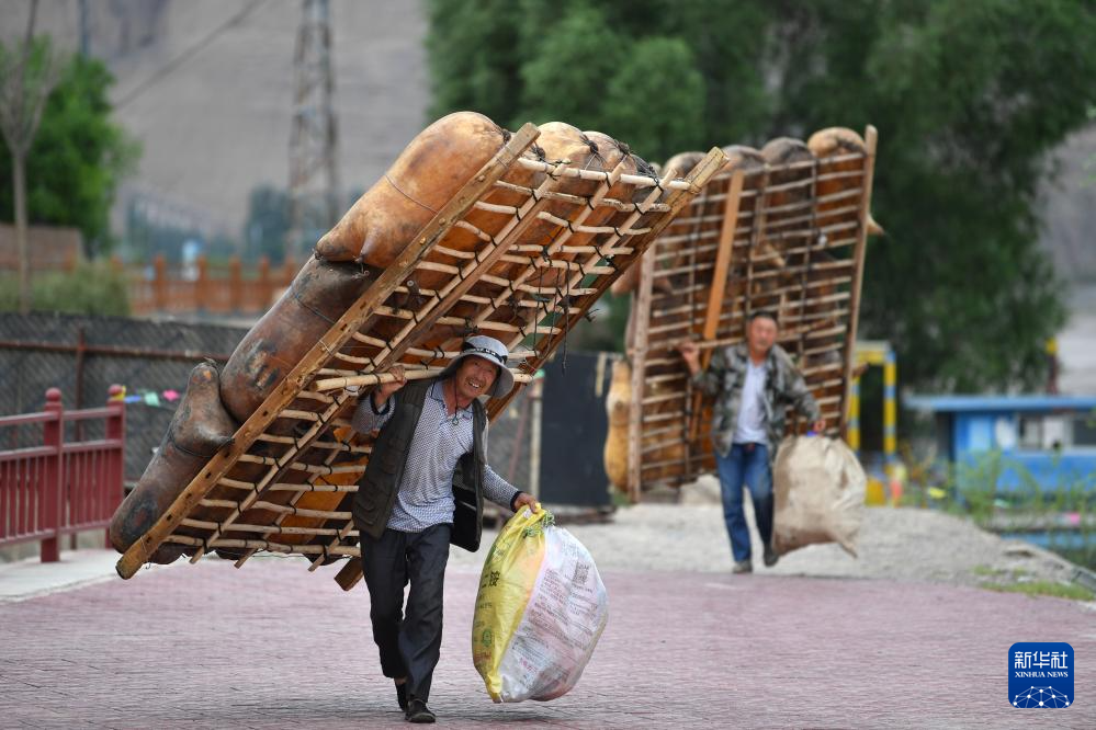 两名筏子客在黄河石林景区背着羊皮筏子准备漂流（7月11日摄） 新华社记者 张可任 摄