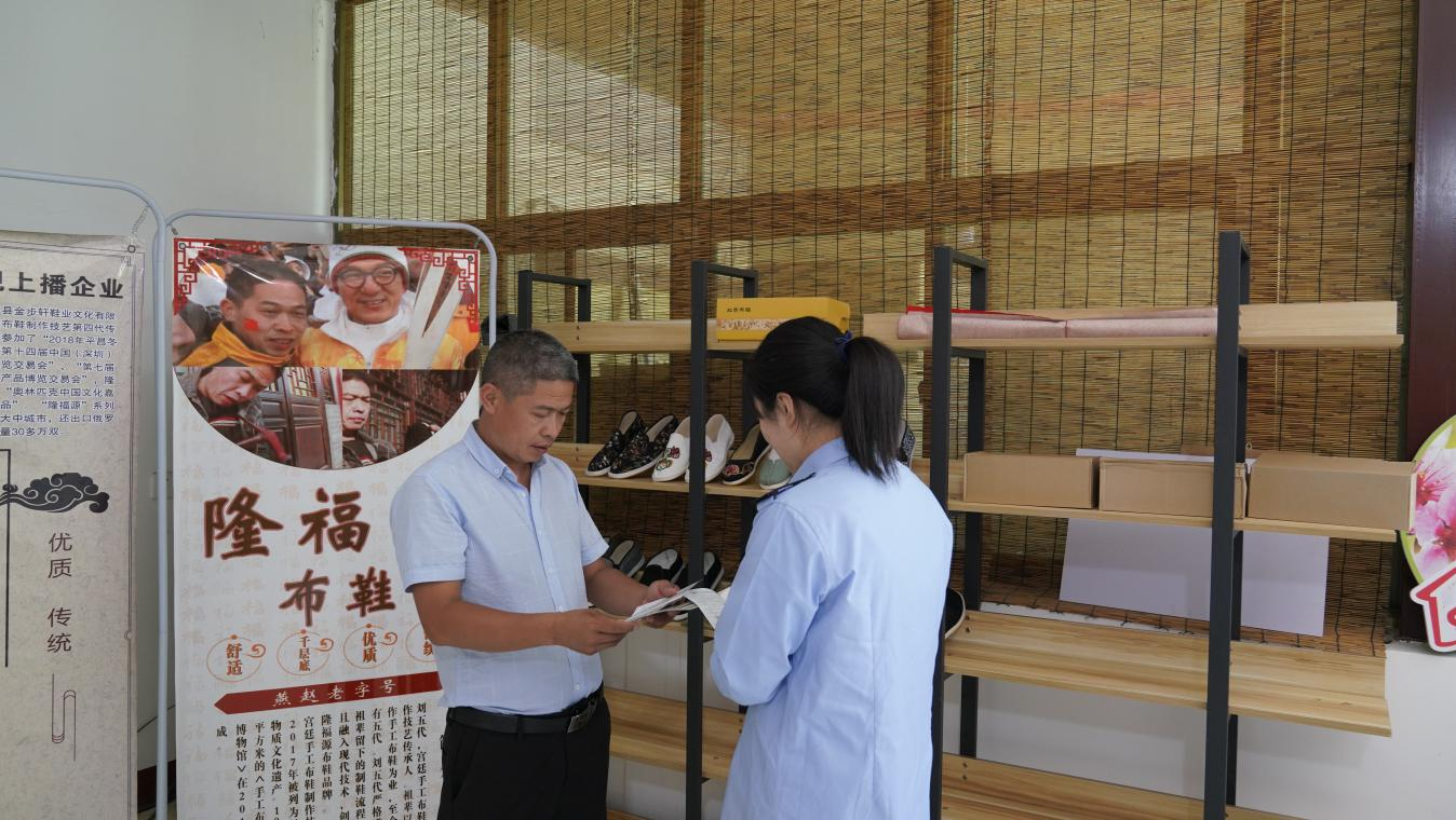 图为税务干部借助农特产品展销会宣讲税费政策，助力手工艺品打通销售渠道