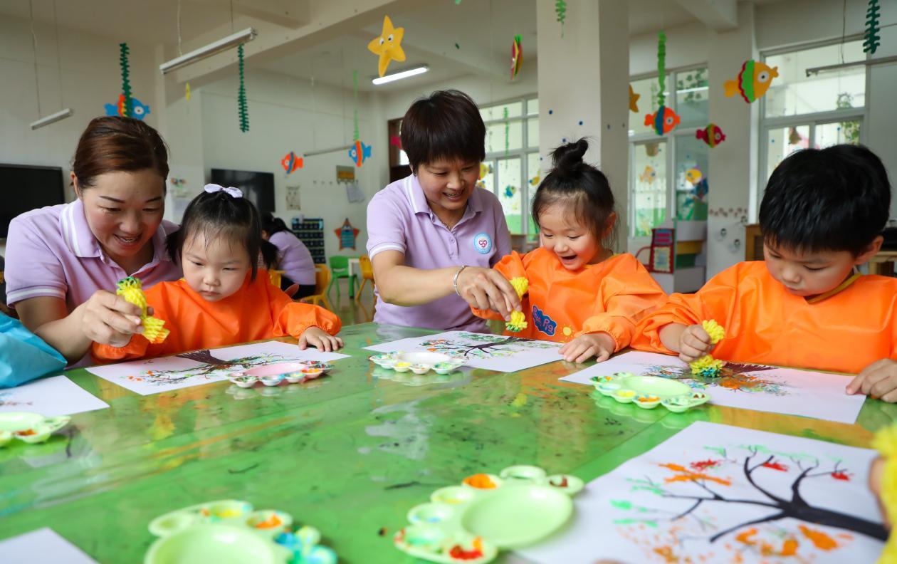 （2023年7月13日，在安徽省合肥市肥西县山南镇中心幼儿园，孩子们在老师的指导下作画。 陈家乐 摄）