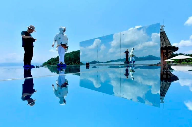 6月25日，游客在宣恩县锣圈岩村一处乡村民宿的“天空之镜”景点游玩。新华社发（宋文摄）