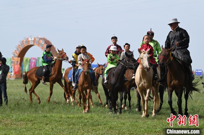 牧民身着民族服饰,骑马在会场附近穿梭,英姿飒爽.