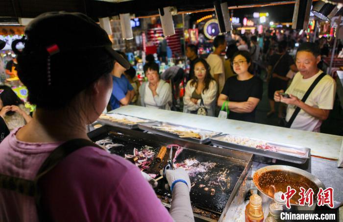 铁板鱿鱼等美食吸引游客品尝。曲正扬 摄