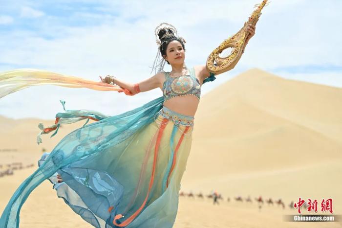 2023年7月21日，甘肃酒泉，敦煌鸣沙山月牙泉景区内，游客身着飞天服饰进行旅拍。如今，人们对于对于敦煌文化的认识有了新的拓展和延伸，敦煌文化变得更加鲜活。李亚龙 摄