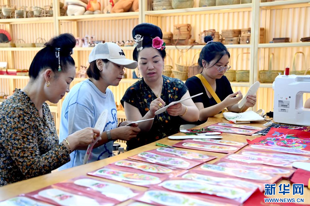 在陕西省汉中市留坝县老街内的一家手工店铺里，当地妇联邀请来自镇巴县的苗绣老师（右二）为当地妇女及游客教授苗绣（7月25日摄）。
