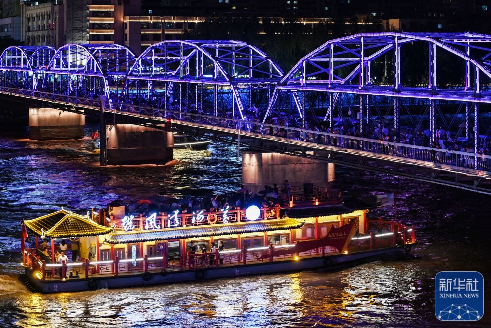 7月26日，游客乘船穿过兰州黄河铁桥——中山桥。