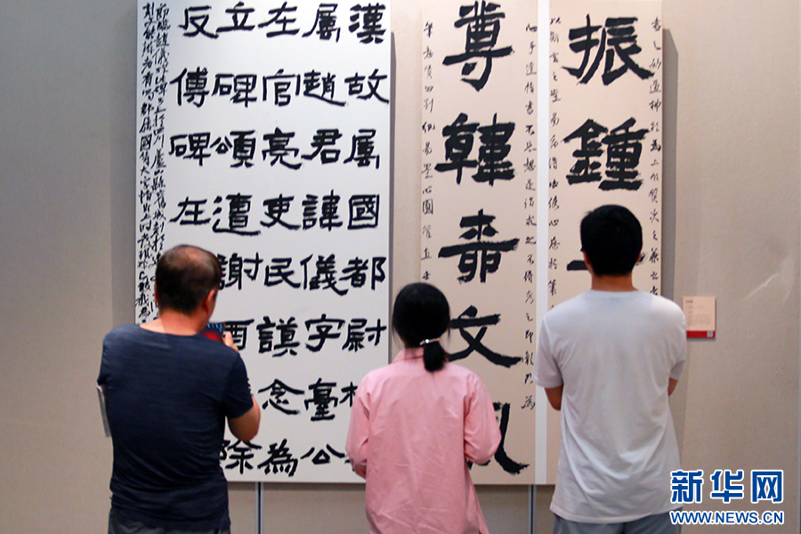 7月24日,在全国第三届书法临帖作品展陕西巡展上,三位观众在观看作品