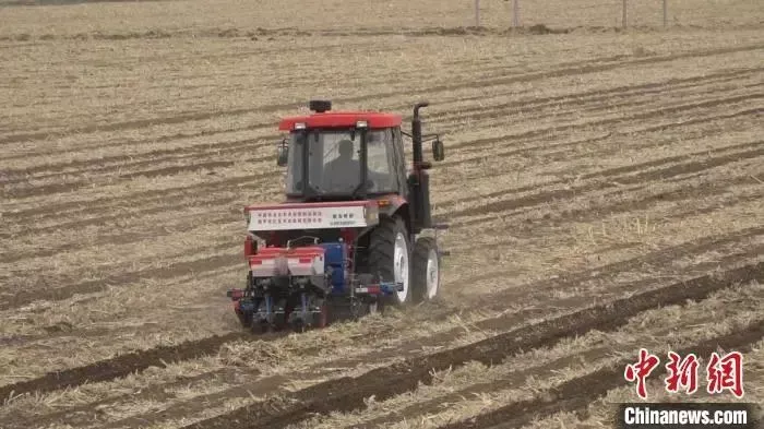 农民正在操作新一代多功能免耕播种机开展春耕工作。　来源：中国新闻网