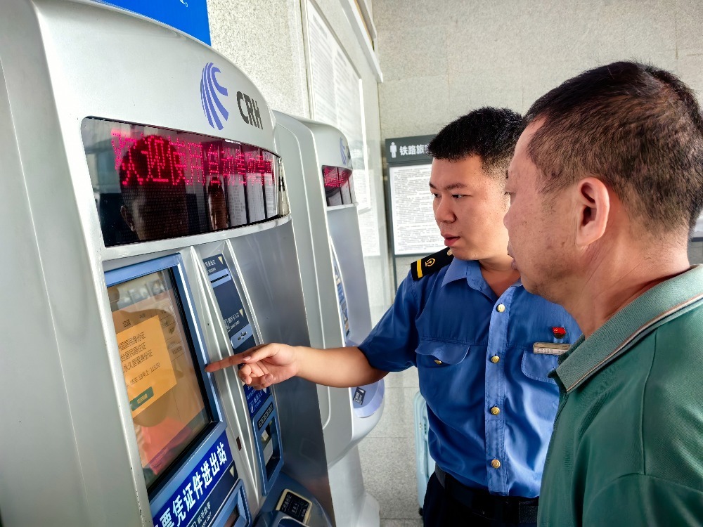 客运值班员游周存在售票厅内教旅客使用自助售票机办理购票。王玉 摄