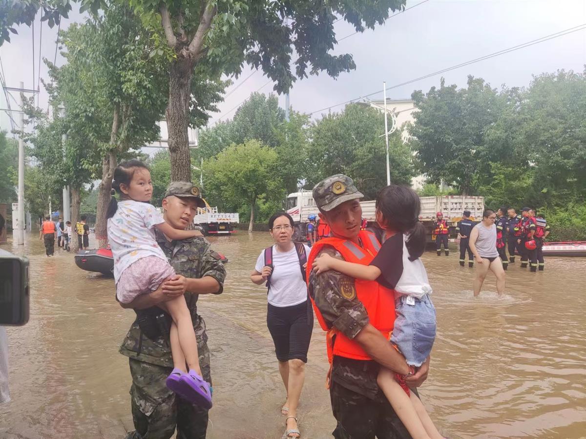 武警官兵在洪水中将被困的儿童抱出。（记者张万军 摄）